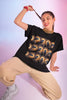 Model wearing a black graphic t-shirt with a vibrant wave design, posing playfully.