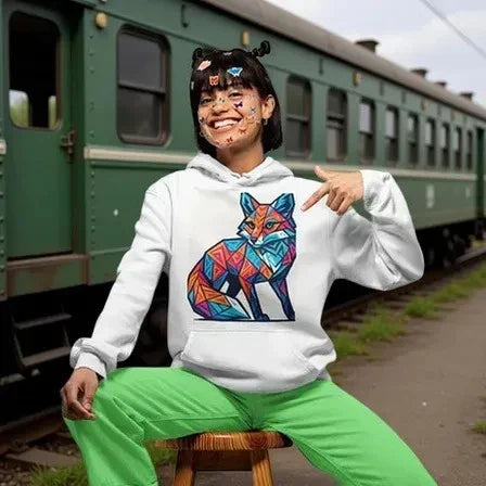 Person in a colorful fox hoodie sitting on a stool near a train.