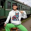 Person in a colorful fox hoodie sitting on a stool near a train.