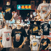 Colorful Taipei street food graphic tees displayed in a lively night market, featuring iconic food motifs and vibrant neon lights
