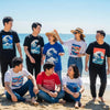 Diverse group wearing Busan-inspired graphic apparel at the beach, showcasing coastal motifs and vibrant colors