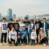 Diverse group wearing K-Pop inspired clothing by the Han River in Seoul, showcasing custom apparel and streetwear aesthetics