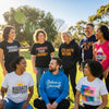 Diverse individuals in affirmation apparel expressing positivity and empowerment in a sunny park