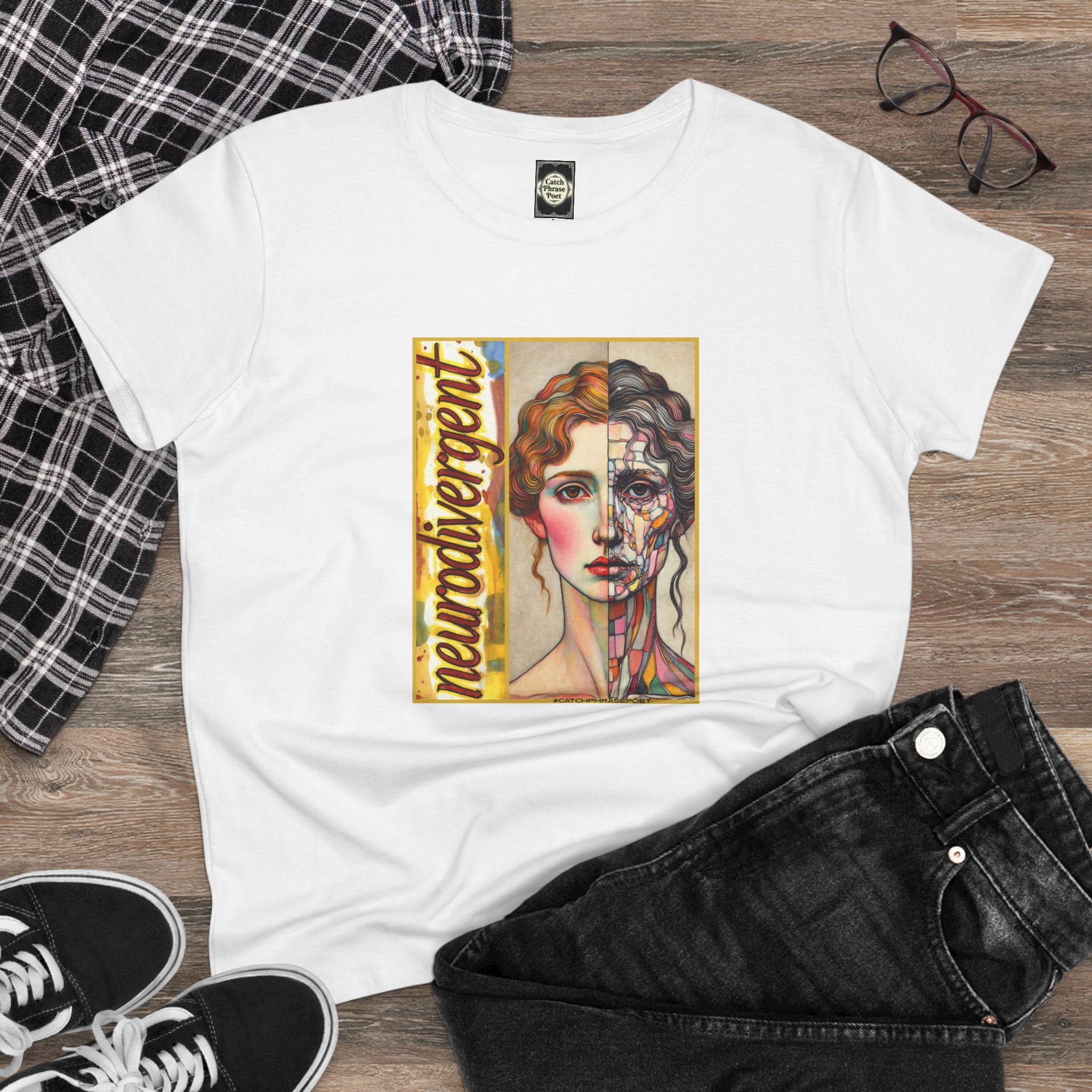 White t-shirt with 'neurodivergent' graphic art of a split-face woman, laid flat with jeans and shoes.