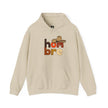 Beige hoodie with 'hombre' text in bold colors and a cowboy hat graphic on the chest