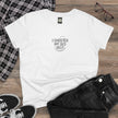White t-shirt with 'Saudade has no translation' text on a wooden surface with casual clothing items.