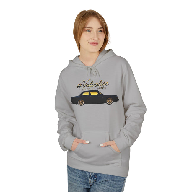 Woman wearing light gray hoodie with Volvolife Swedish brick car graphic and blue jeans