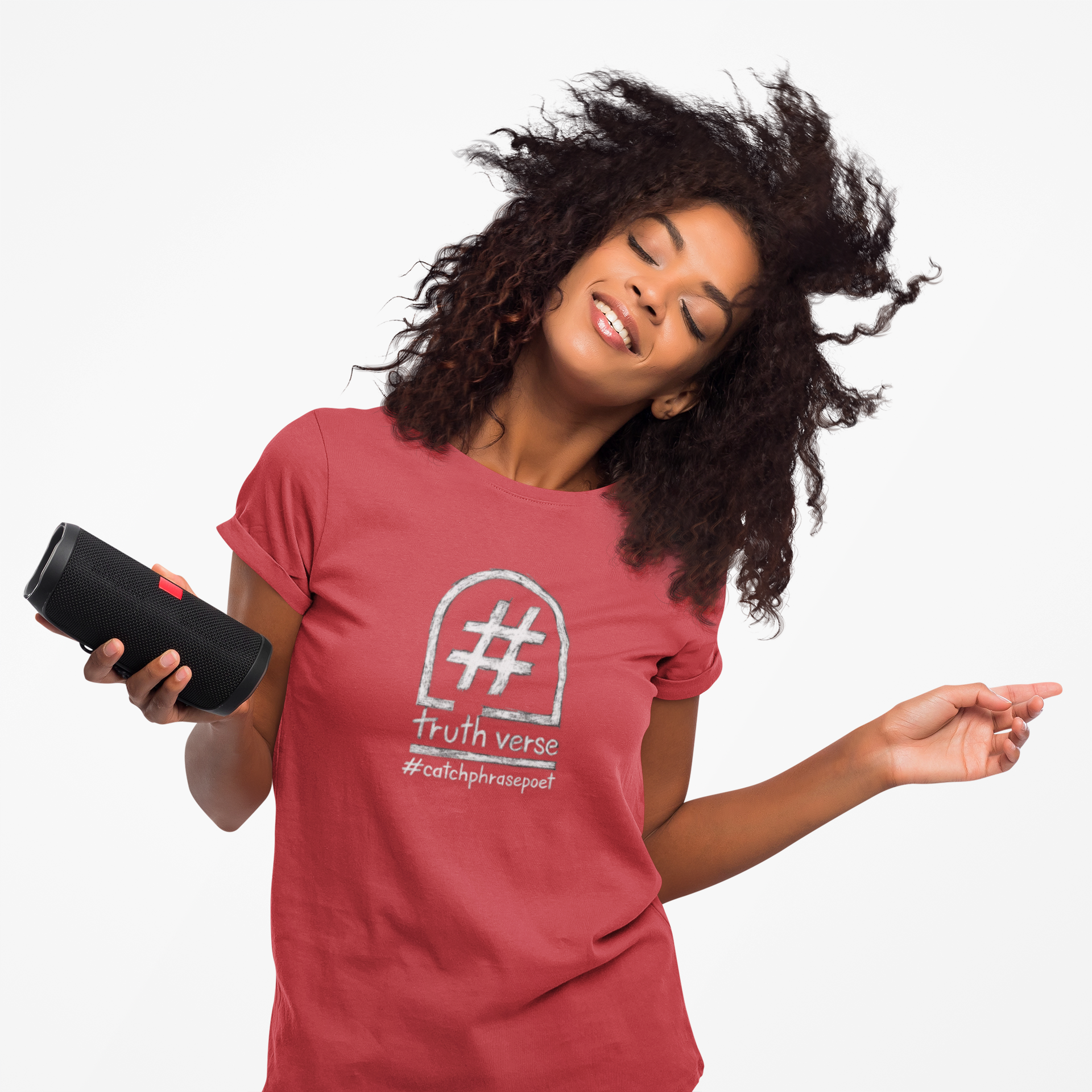 Smiling woman in red graphic tee with hashtag slogan, enjoying music on portable speaker