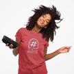 Smiling woman in red graphic tee with hashtag slogan, enjoying music on portable speaker