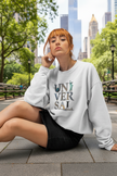 Woman in white sweatshirt with colorful 'UNIVERSAL' graphic, seated against white background.