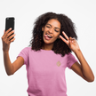 Woman in pink t-shirt taking selfie, making peace sign, casual creative style