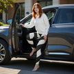 Woman in black and white leggings and white sweater stepping out of parked car outdoors