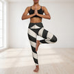 Woman practicing yoga in black sports bra and geometric striped leggings in bright studio