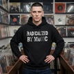 Man wearing a black hoodie with 'RADICALIZED BY MUSIC' text in a record store.