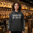 Person wearing a hoodie with 'Radicalized by Music' text in a guitar store.