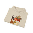Beige hoodie folded with 'hombre' text, cowboy hat graphic, and #catchphrasepoet on front