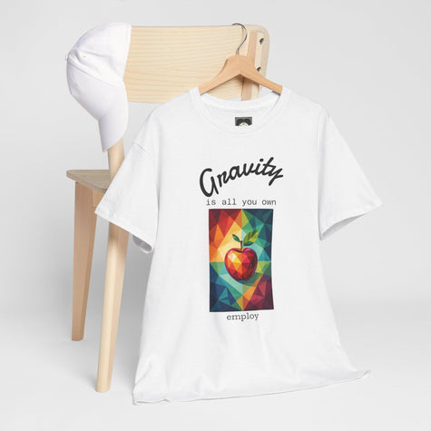 White T-shirt with geometric apple art and 'Gravity is all you own' quote, styled on chair with cap.