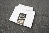 White hoodie with 'Here comes Trouble' text and dice design on a white background
