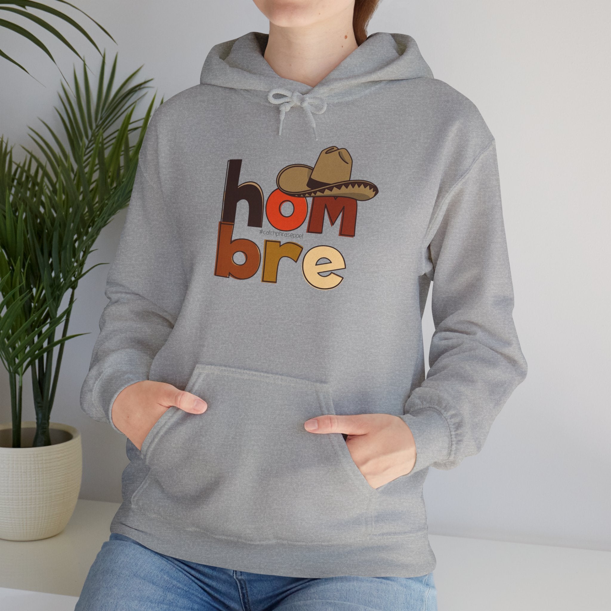 Person wearing gray hoodie with 'hombre' text and sombrero graphic, casual clothing style