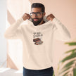 Man wearing a beige hoodie with a graphic design and text, standing against a neutral background.