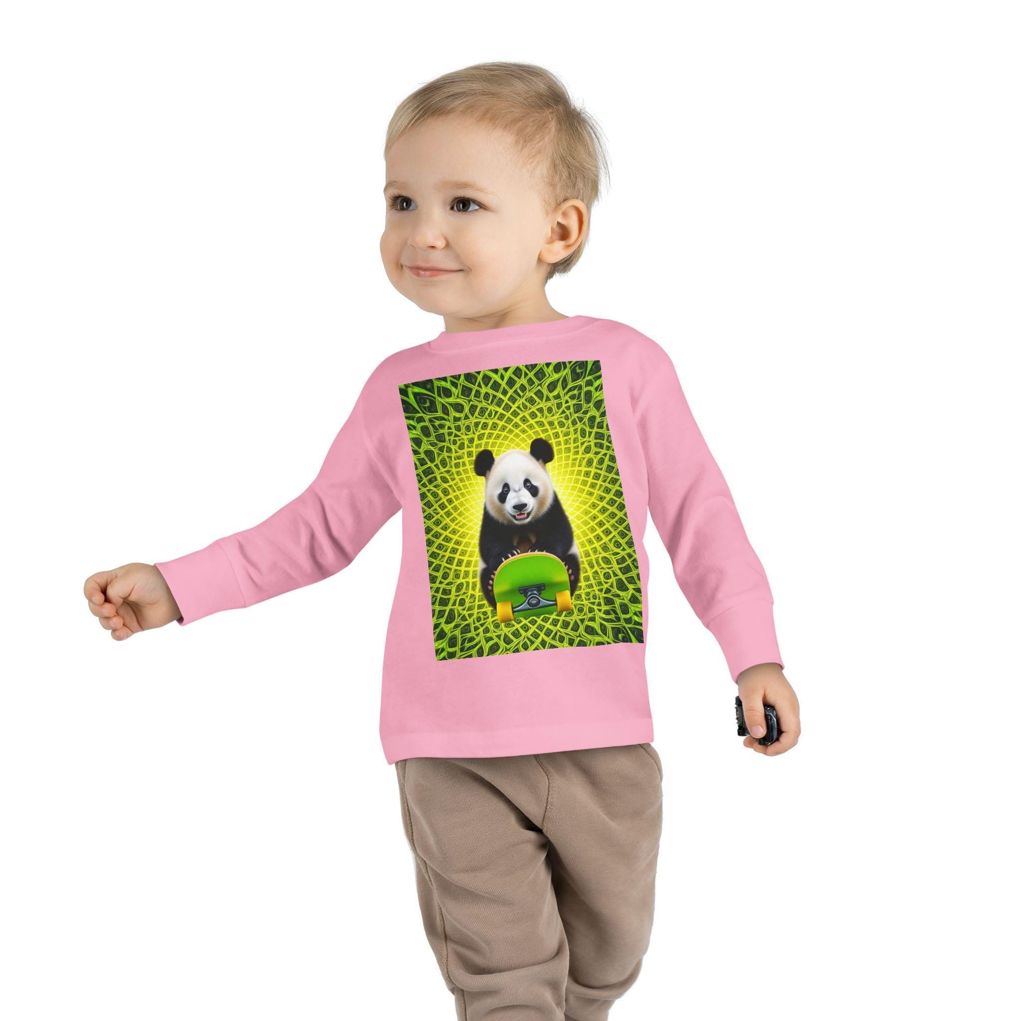 Toddler in pink sweatshirt with panda and skateboard graphic, green geometric background