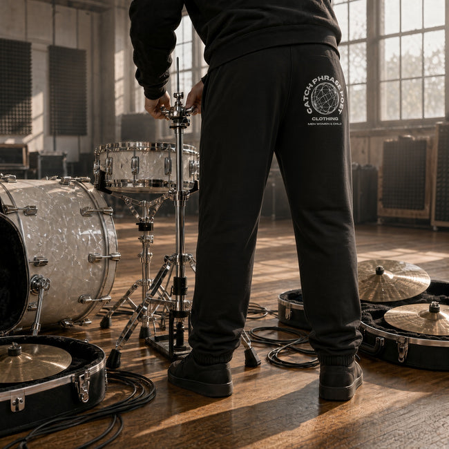 Man setting up a drum kit wearing Radicalized by Music fleece joggers — Catch Phrase Poet