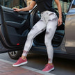 Woman in geometric print leggings and pink sneakers stepping out of a car