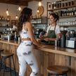 Woman in star print activewear at coffee shop counter talking to barista