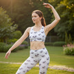 Woman practicing yoga outdoors in patterned activewear set, serene garden background
